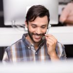 Smiling male customer service executive talking on headset at desk in office